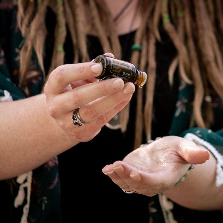 Hände mit ätherischem Ölfläschchen und geöffneter Handfläche.