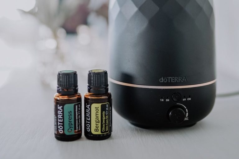 Ätherische Öle in Flaschen neben einem schwarzen Aroma-Diffusor.